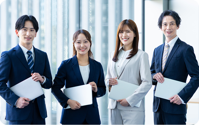 4人の男女のグループがスーツ姿でパソコンを抱えている画像